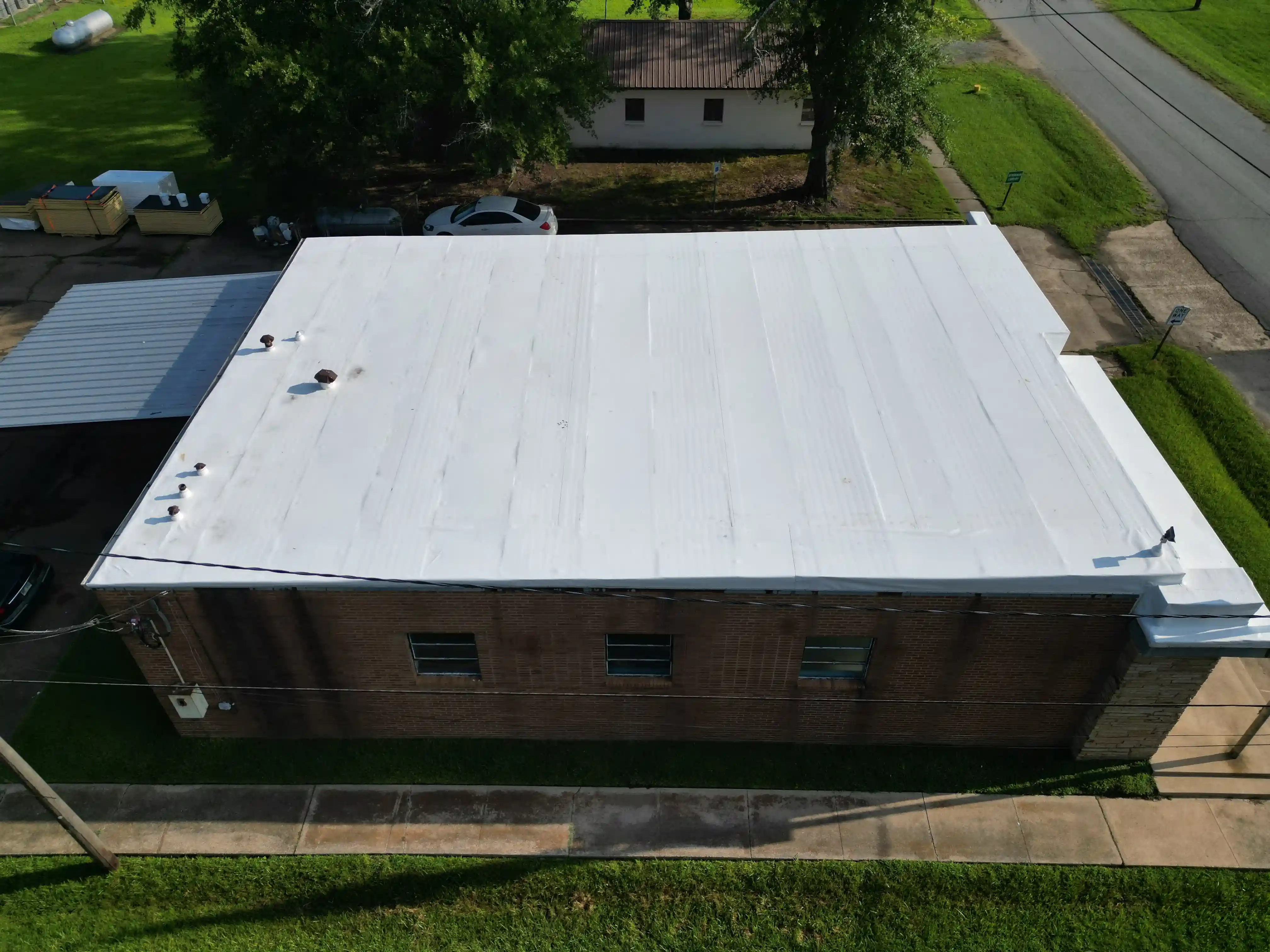 Wide flat white membrane roof spanning a low-slope industrial-scale building